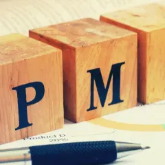 Drewniane klocki z literami P, M, I. Czy to jest PMI, czyli wskaźnik aktywności gospodarczej? Obok długopis i wykres.