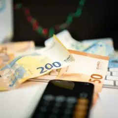 Euro banknoty na klawiaturze, telefon i wykres giełdowy sugerują, jak inwestować w waluty.