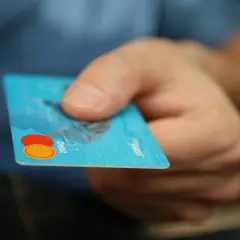Dłoń trzyma kartę debetową. Ktoś zapłacił moją kartą przez internet, co jest niepokojące.