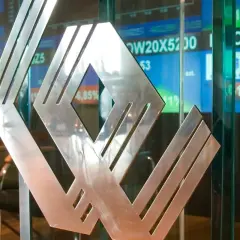 Metalowe logo na tle ekranów giełdowych. Asbis rekomendacje widać na wykresach.