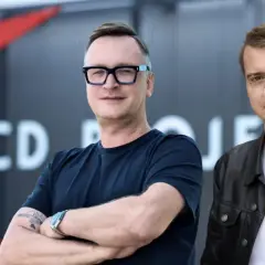 Dwóch mężczyzn na tle logo CD Projekt. Analiza przyszłości firmy.