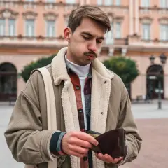 Młody mężczyzna z pustym portfelem w ręku, smutny wyraz twarzy. Inflacja stylu życia dotyka każdego.