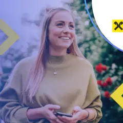 Uśmiechnięta kobieta z telefonem w ręku, korzystająca z usług Raiffeisen Digital Bank.