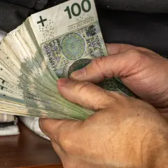 Dłonie trzymające plik banknotów 100 zł. Symbol oszczędności Polaków, być może na czarną godzinę lub na wymarzone wakacje.
