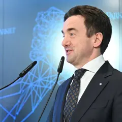 Mężczyzna w garniturze przemawia przy mikrofonach. Na ekranie w tle logo "Parkiet" i schemat sieci. Giełda Papierów Wartościowych (GPW) i bankierzy dyskutują o przyszłości.