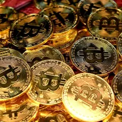 Złote monety z symbolem Bitcoina, symbolizujące jego wartość.