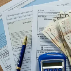 Formularze podatkowe PIT, długopis, kalkulator i banknoty 200 zł. Czas na rozliczenie podatku, zbliża się ikze limit 2026.