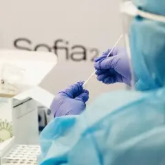 Osoba w kombinezonie i rękawiczkach przygotowuje testy Sofia SARS Antigen. To ważny kurs, który pomaga w diagnostyce.
