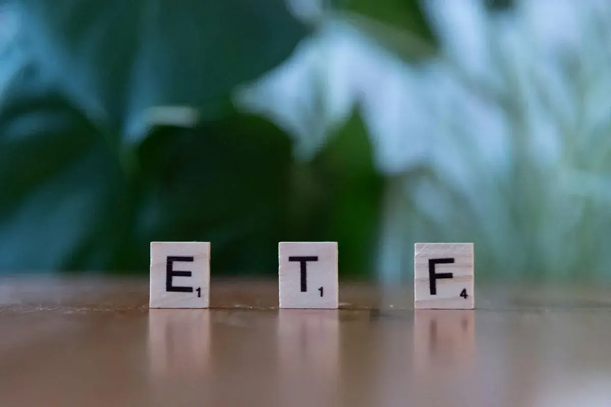 Litery ETF na drewnianych klockach symbolizują inwestycje, które mogą pomóc w nauce, jak zarabiać na giełdzie.