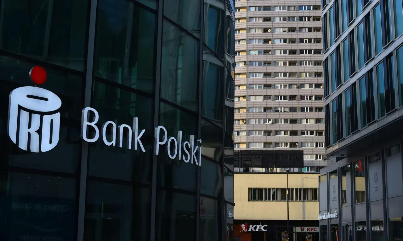 Logo PKO Bank Polski na szklanej fasadzie. W tle blok mieszkalny i KFC. PKO BP rekomendacje.