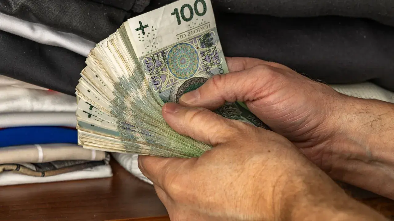 Dłonie trzymające plik banknotów 100 zł. Symbol oszczędności Polaków, być może na czarną godzinę lub na wymarzone wakacje.