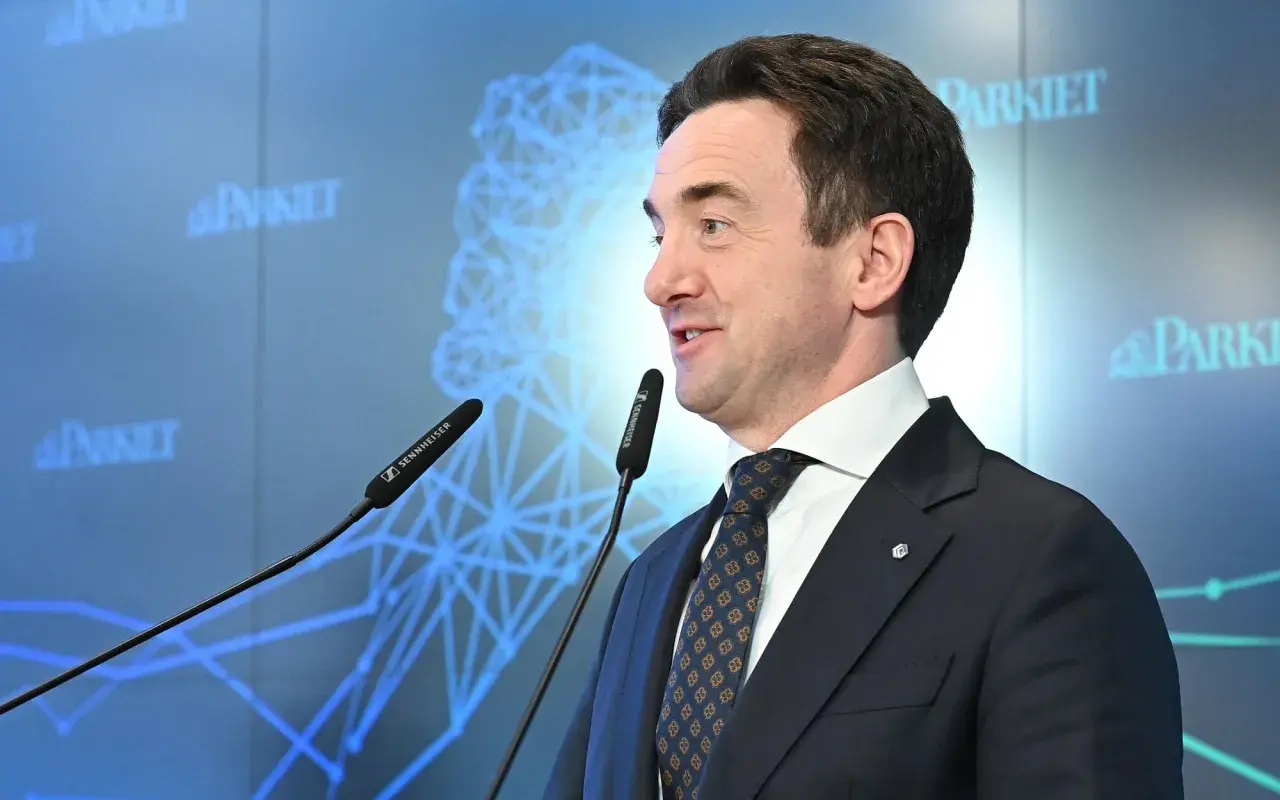Mężczyzna w garniturze przemawia przy mikrofonach. Na ekranie w tle logo "Parkiet" i schemat sieci. Giełda Papierów Wartościowych (GPW) i bankierzy dyskutują o przyszłości.