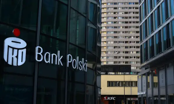 Logo PKO Bank Polski na szklanej fasadzie. W tle blok mieszkalny i KFC. PKO BP rekomendacje.